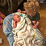 baby, blanket, caring, child, curious, curly_hair, family, floor, home, indoor, infant, looking, newborn, pacifier, person, soft_texture, toddler, warm, wood_floor, wrapped