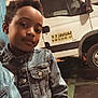 child, denim_jacket, vehicle, van, garage, indoor, person, casual, portrait, young, black_hair, smile, clothing, transport, parking, floor, head, face, window, door