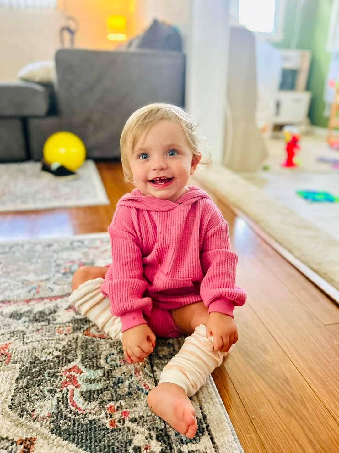 Abigail is registered to the contest to win money with this photo: baby_toddler_clothing, child, floor, flooring, happy, hardwood, joy, magenta, pattern, person, photograph, play, room, sitting, sleeve, smile, t_shirt, toddler, wood, wood_flooring