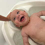 Mya a rejoint le concours — aidez-le/la à gagner de superbes lots ! baby, bath, water, smile, happy, child, skin, head, hand, necklace, infant, cute, playful, splash, indoors, tub, wet, person, closeup, joy