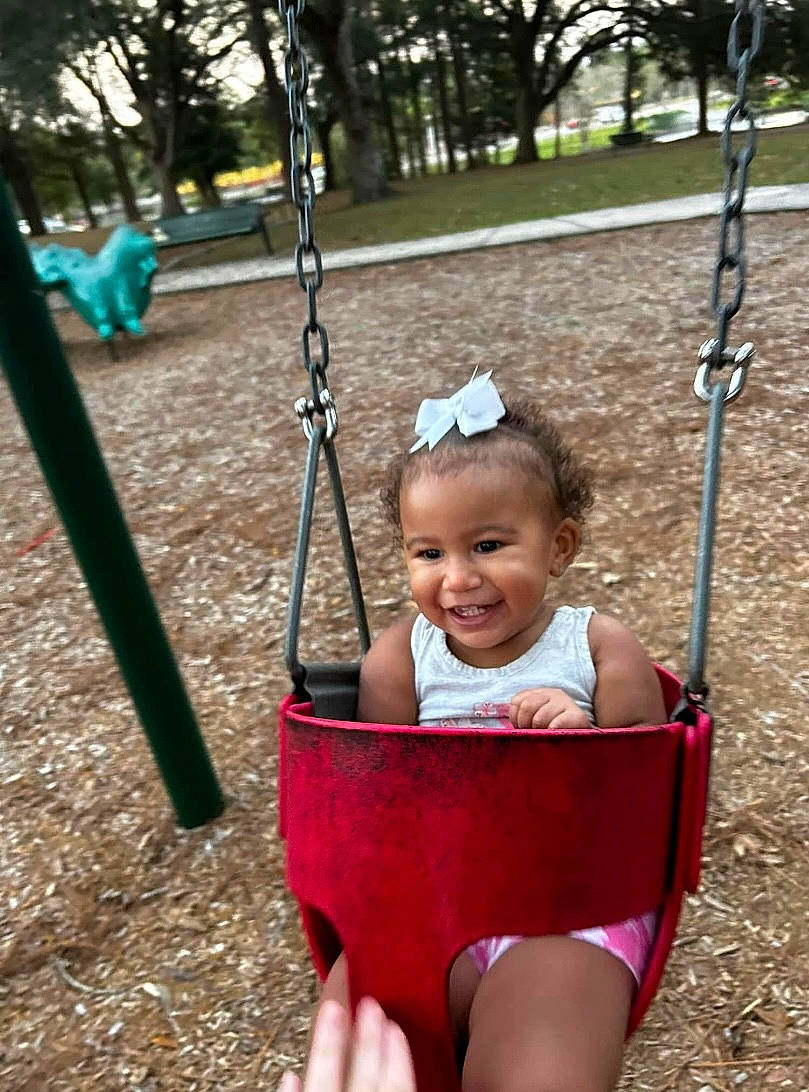 Kaliyah joined the competition — help win amazing prizes! baby, black, fun, grass, green, happy, joy, leaf, leisure, people, person, photograph, plant, playground, public_space, smile, summer, swing, toddler, tree