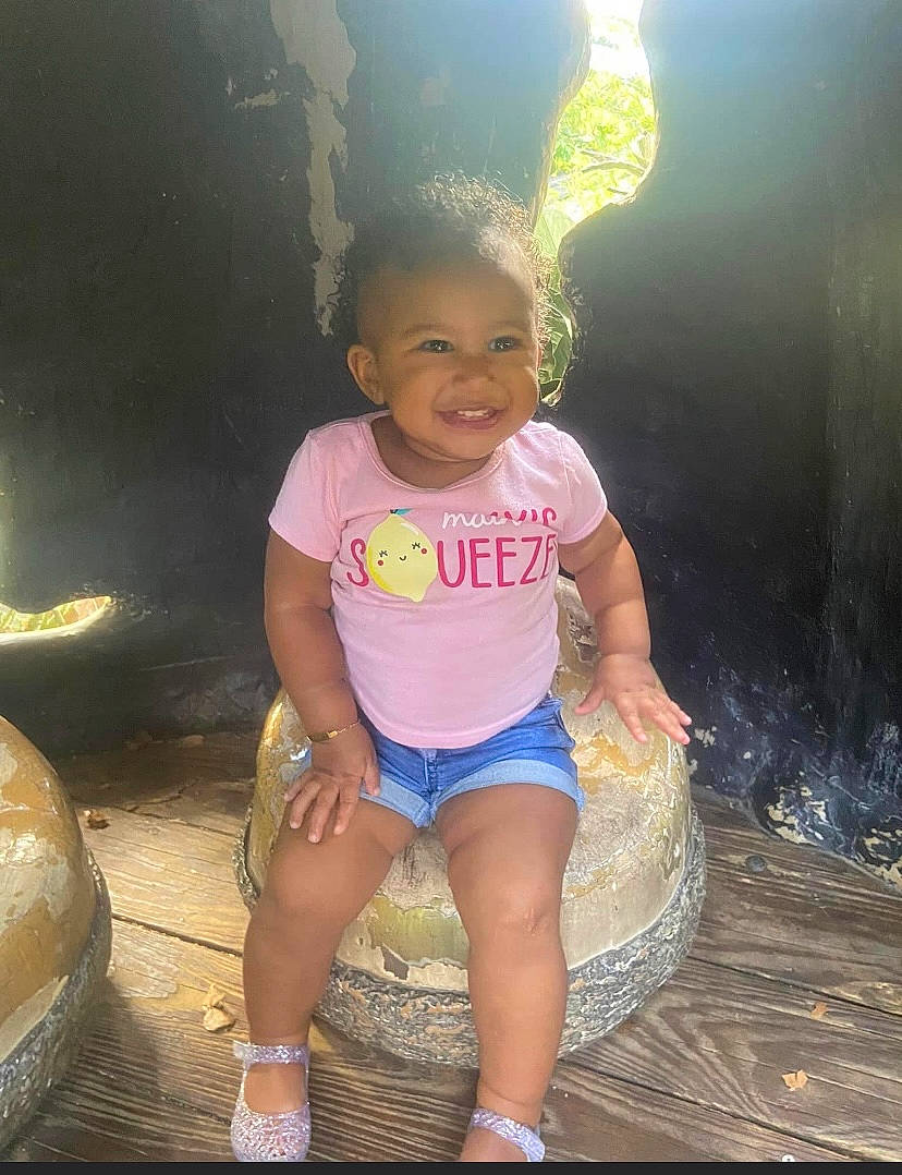 Kaliyah joined the competition — help win amazing prizes! baby_toddler_clothing, child, cool, flash_photography, fun, grass, happy, human_leg, joy, leisure, magenta, person, recreation, sandal, shorts, sitting, smile, t_shirt, thigh, toddler