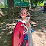 Naé participe au concours pour gagner de l'argent avec cette photo : barefoot, child, daylight, fence, ground, happy, leaves, nature, outdoor, park, person, pigtails, play, playground, red, rocker, shadow, smiling, sunlight, tree