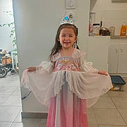 Naé participe au concours pour gagner de l'argent avec cette photo : appliance, cabinet, child, curtain, dress, footwear, girl, gown, happy, home, indoor, kitchen, light, long_hair, person, pose, princess, smile, tiara, tile_floor