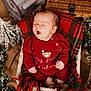 Caleb is registered to the contest to win money with this photo: baby, infant, red_clothing, plaid_blanket, basket, christmas, holiday, decorations, lights, berries, pine_branches, yawning, cozy, festive, knitwear, cute, sleepy, indoors, holiday_season, celebration