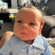 Caleb joined the competition — help win amazing prizes! baby, infant, face, blue_clothing, closeup, person, indoors, furniture, couch, blanket, buttoned_shirt, curtains, soft_light, carpet, hand, newborn, expression, cute, child, portrait