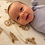 Caleb is registered to the contest to win money with this photo: baby, infant, smile, blanket, bear_pattern, onesie, clothing, face, head, lying_down, happy, cute, soft_texture, cozy, indoor, portrait, child, newborn, baby_boy, bed