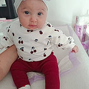 Kayleen a rejoint le concours — aidez-le/la à gagner de superbes lots ! baby, child, headband, bow, cherry_pattern, red_pants, white_socks, infant, cute, portrait, indoor, soft_lighting, supporting_arm, baby_supplies, changing_table, expression, sitting, clothing, person, face