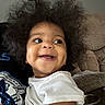 toddler, child, smile, happy, curly_hair, white_shirt, indoor, person, face, couch, furniture, skin, portrait, cute, baby, young_child, joy, expression, sitting, human