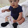 Miguel is registered to the contest to win money with this photo: baby, bed, blanket, child, clothing, cozy, curious, cute, expression, face, hand, home, indoor, infant, person, portrait, sitting, snack, socks, young