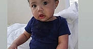 Miguel is registered to the contest to win money with this photo: baby, bed, blanket, child, clothing, curious, expression, face, feet, footwear, indoors, infant, light, onesie, person, portrait, sitting, socks, window, young_child