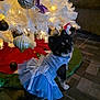dog, dress, blue_dress, christmas_tree, ornaments, white_tree, holiday, festive, lights, floor, tile_floor, decorations, pet, cute, small_dog, indoor, celebration, seasonal, christmas, posing