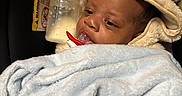 A Zyiss is registered to the contest to win money with this photo: baby, infant, child, portrait, sleeping, bottle, pacifier, blanket, hat, fluffy, animal_hat, bundled, cozy, indoors, close_up, face, eyes, warm_lighting, seated, newborn