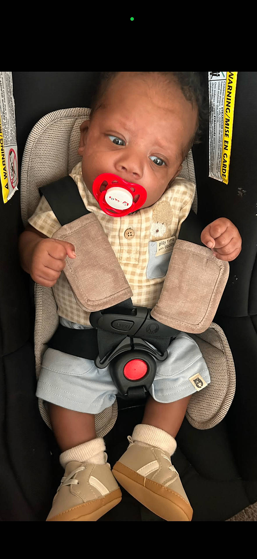 A Zyiss is registered to the contest to win money with this photo: baby, blue_eyes, brown_hair, car_seat, child, close_up, clothing, fashion, hands, indoor, infant, pacifier, plaid_shirt, portrait, safe, safety_harness, shorts, sitting, sneakers, vehicle_interior