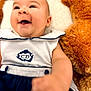 baby, smiling, infant, clothing, teddy_bear, soft, cute, portrait, child, happy, face, cuddly, toy, white, navy_blue, fabric, person, closeup, indoor, cozy