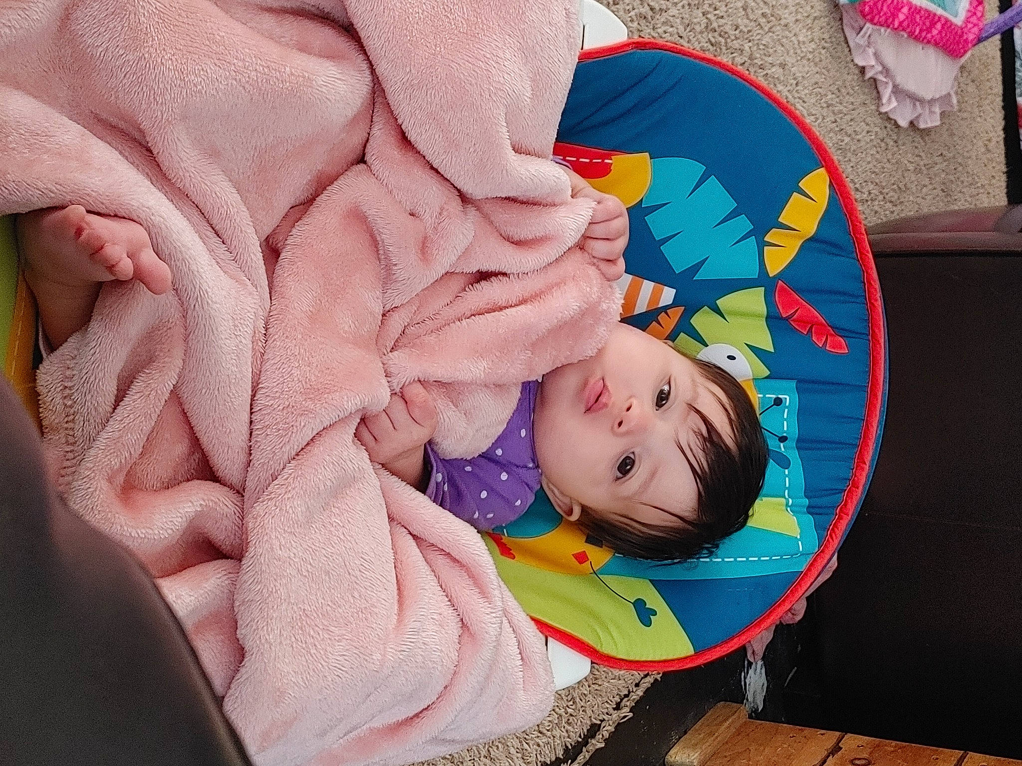 Delila is registered to the contest to win money with this photo: baby, baby_products, baby_toddler_clothing, carmine, cheek, child, comfort, facial_expression, fashion_accessory, flooring, happy, leisure, linens, magenta, person, pink, sitting, sleeve, textile, toddler