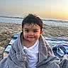 María Jose Sua Baron is registered to the contest to win money with this photo: toddler, child, smiling, towel, beach, sand, ocean, sunset, blanket, striped, hair, clothing, outdoor, happy, portrait, sitting, cute, baby, face, warm