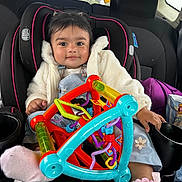 María Jose Sua Baron joined the competition — help win amazing prizes! baby, car_seat, toy, child, smile, clothing, jacket, sock, car_interior, seatbelt, headrest, window, cupholder, purple_bag, plastic_toy, child_protection, cute, infant, portrait, happy