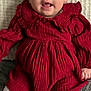 Tallulah joined the competition — help win amazing prizes! baby, child, red_dress, white_tights, knitted_tights, textured_clothing, sitting, indoor, blanket, curious_expression, face, head, hands, feet, portrait, infant, cozy, cute, young_child, person