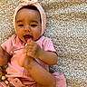 baby, blanket, child, comfortable, cute, expression, face, foot_in_mouth, hand, happy, headband, indoors, infant, lying_down, patterned_blanket, pink_clothing, playful, skin, toddler, young_child