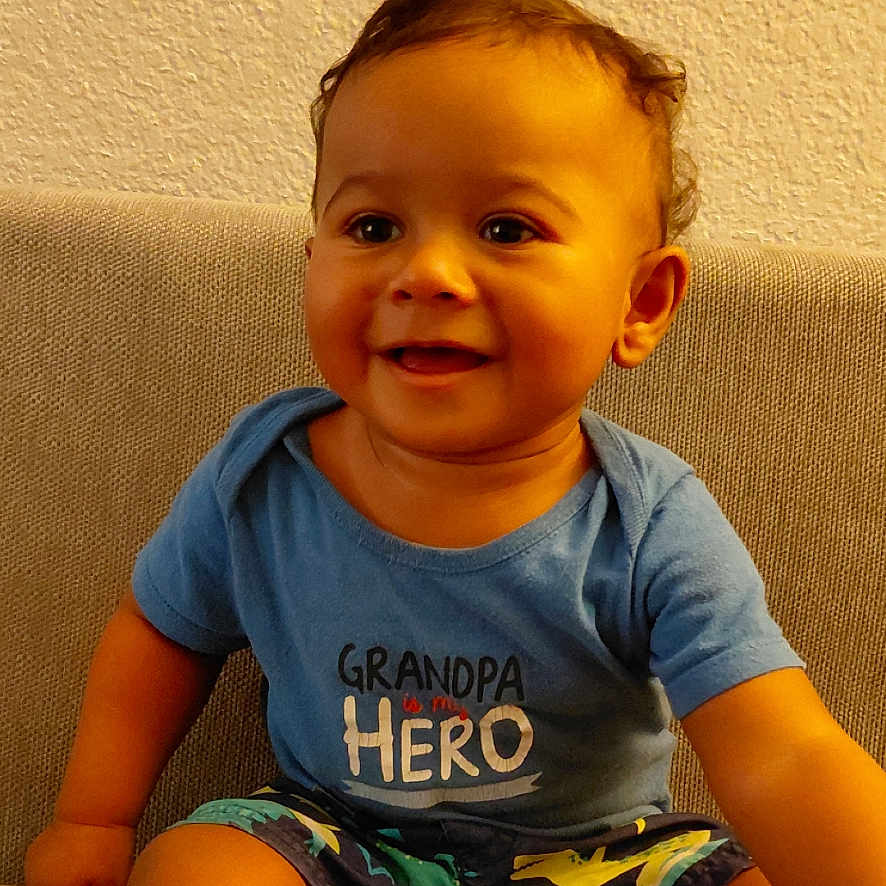 Aldeunte is registered to the contest to win money with this photo: baby, bare_feet, blue_shirt, child, couch, event_alert, face, furniture, hair, happy, home, indoor, lock_screen, phone_screenshot, portrait, printed_shirt, shorts, sitting, smiling, toddler