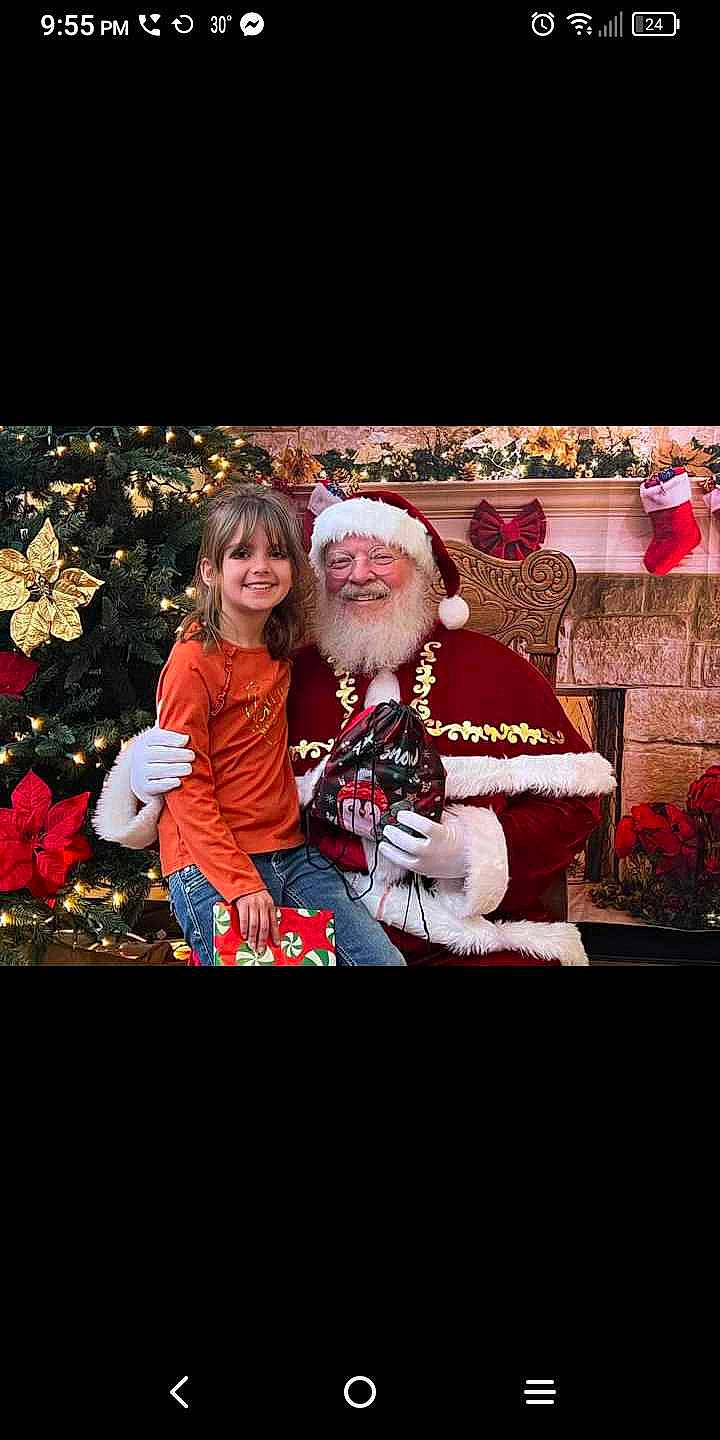 Allyssandra joined the competition — help win amazing prizes! beard, christmas, christmas_decoration, christmas_eve, christmas_ornament, event, facial_hair, fictional_character, fun, happy, hat, headwear, holiday, joy, lap, person, plant, room, santa_claus, smile