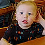 Timothy joined the competition — help win amazing prizes! child, toddler, blue_eyes, indoor, wooden_table, wooden_chair, patterned_shirt, curious, person, face, hand, seated, furniture, casual_clothing, young_child, light_skin, short_hair, tabletop, restaurant, background_people