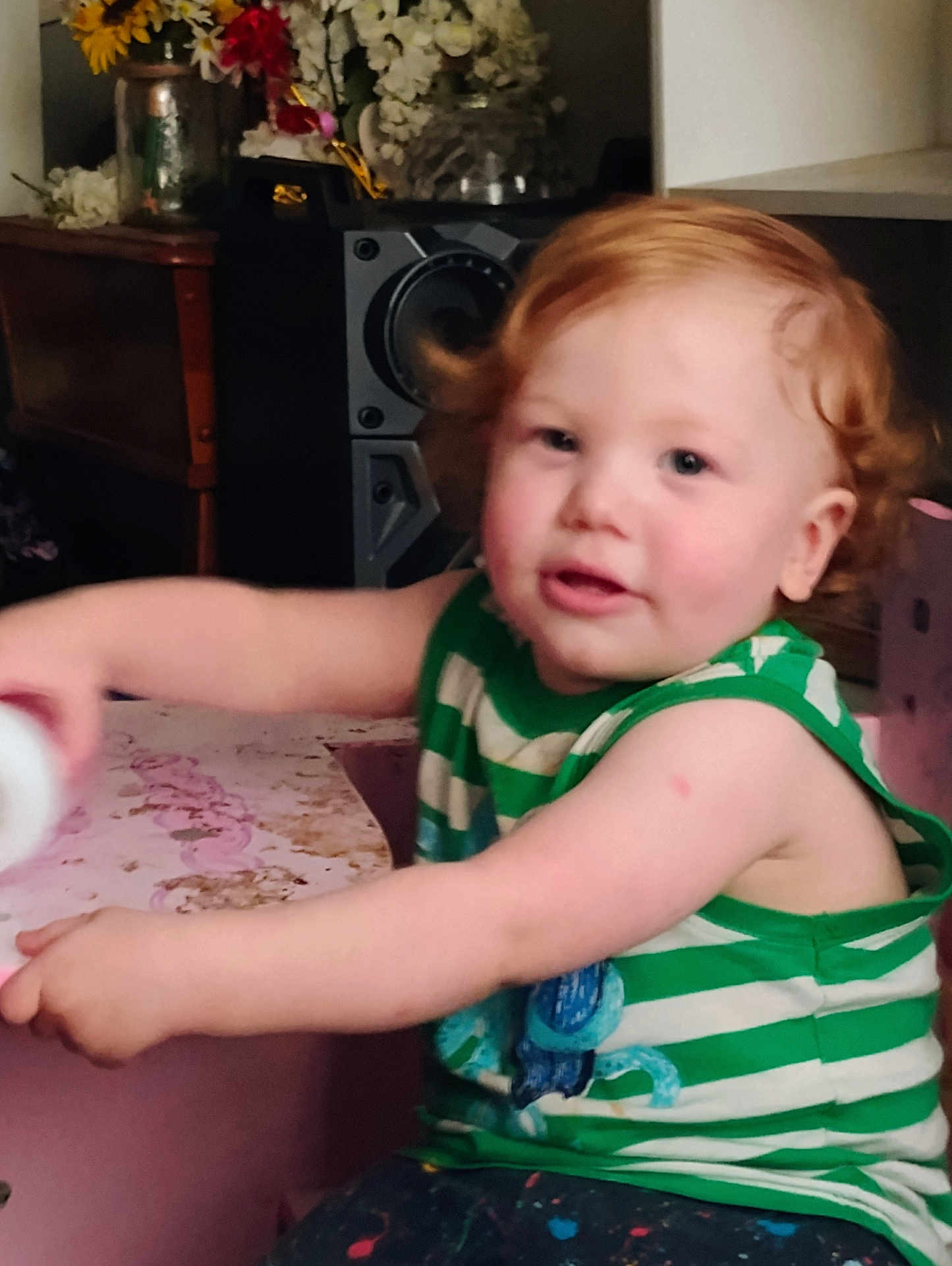 Timothy joined the competition — help win amazing prizes! toddler, child, curly_hair, red_hair, green_shirt, striped_clothing, indoor, playful, furniture, flowers, table, person, young_child, cute, smiling, skin, face, arm, expression, home