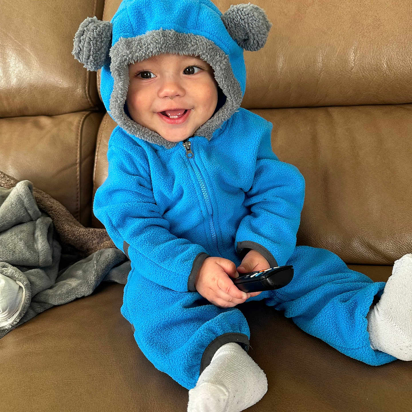 Alejo is registered to the contest to win money with this photo: baby, bodypart, clothing, coat, couch, face, finger, furniture, hand, hat, head, hood, hosiery, jacket, pants, person, photography, portrait, sitting, sock