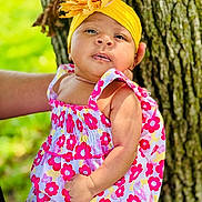 Serena joined the competition — help win amazing prizes! baby, child, flower_headband, yellow_headband, pink_flower_dress, tree, outdoor, nature, green_background, person, infant, cute, portrait, skin, hand, summer, sunlight, colorful_clothing, closeup, baby_fashion