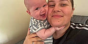 Logan is registered to the contest to win money with this photo: adult, baby, casual, cheek, closeup, couch, face, family, hand, happy, head, holding, indoor, love, person, portrait, skin, smile, striped_clothing, together