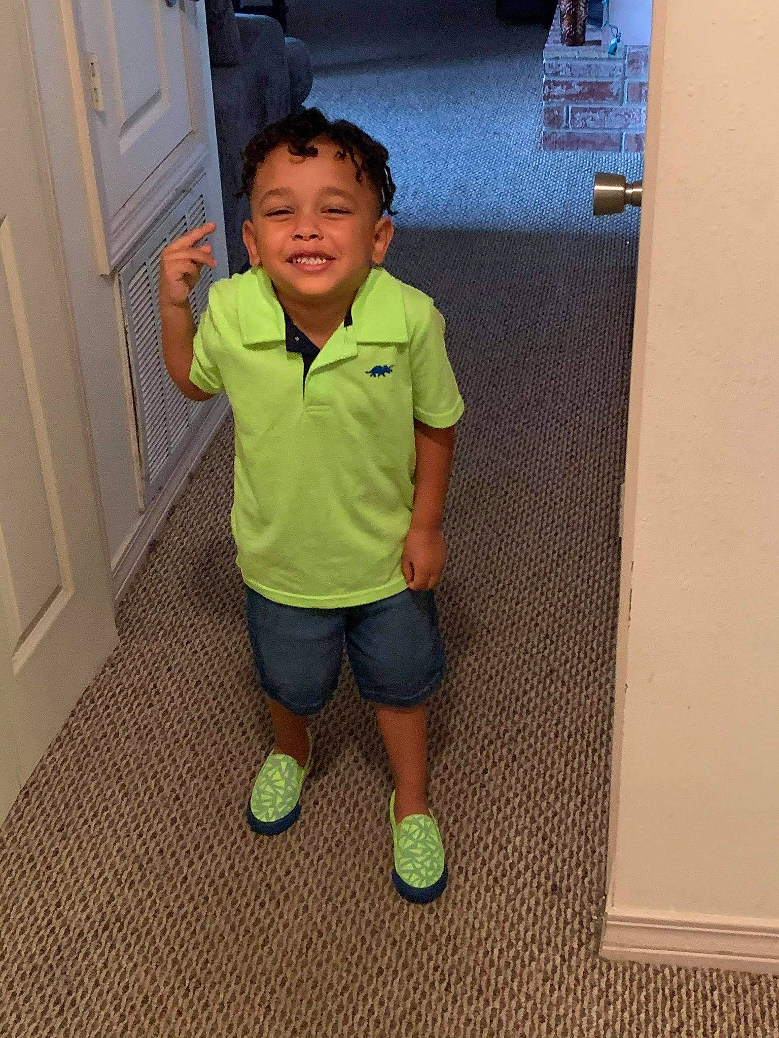 Zayden is registered to the contest to win money with this photo: arm, child, cool, face, finger, floor, flooring, footwear, green, head, joint, joy, leg, outerwear, person, shoe, shoulder, skin, standing, t_shirt