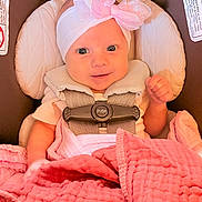 Marion is registered to the contest to win money with this photo: baby, infant, car_seat, pink_bow, headband, blanket, smile, child, safety_harness, cute, indoors, person, clothing, seat, comfort, newborn, portrait, happy, baby_girl, wrapped