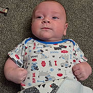 Tucker is registered to the contest to win money with this photo: baby, infant, carpet, onesie, blanket, fist, clothing, lying_down, face, head, person, child, cute, indoor, pattern, animal_print, expression, young, baby_girl, baby_boy