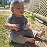 toddler, child, bunny_ears, blue_ears, grass, outdoor, sunny, toy, blue_toy, fence, wooden_fence, baby, sitting, barefoot, clothing, short_sleeves, curly_hair, nature, daylight, portrait