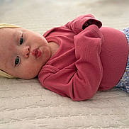 Layla joined the competition — help win amazing prizes! baby, infant, portrait, lying_down, bed, quilt, pink_clothing, floral_clothing, headband, bow, face, eyes, baby_face, indoors, close_up, adorable, serious_expression, fashion, textile, photography