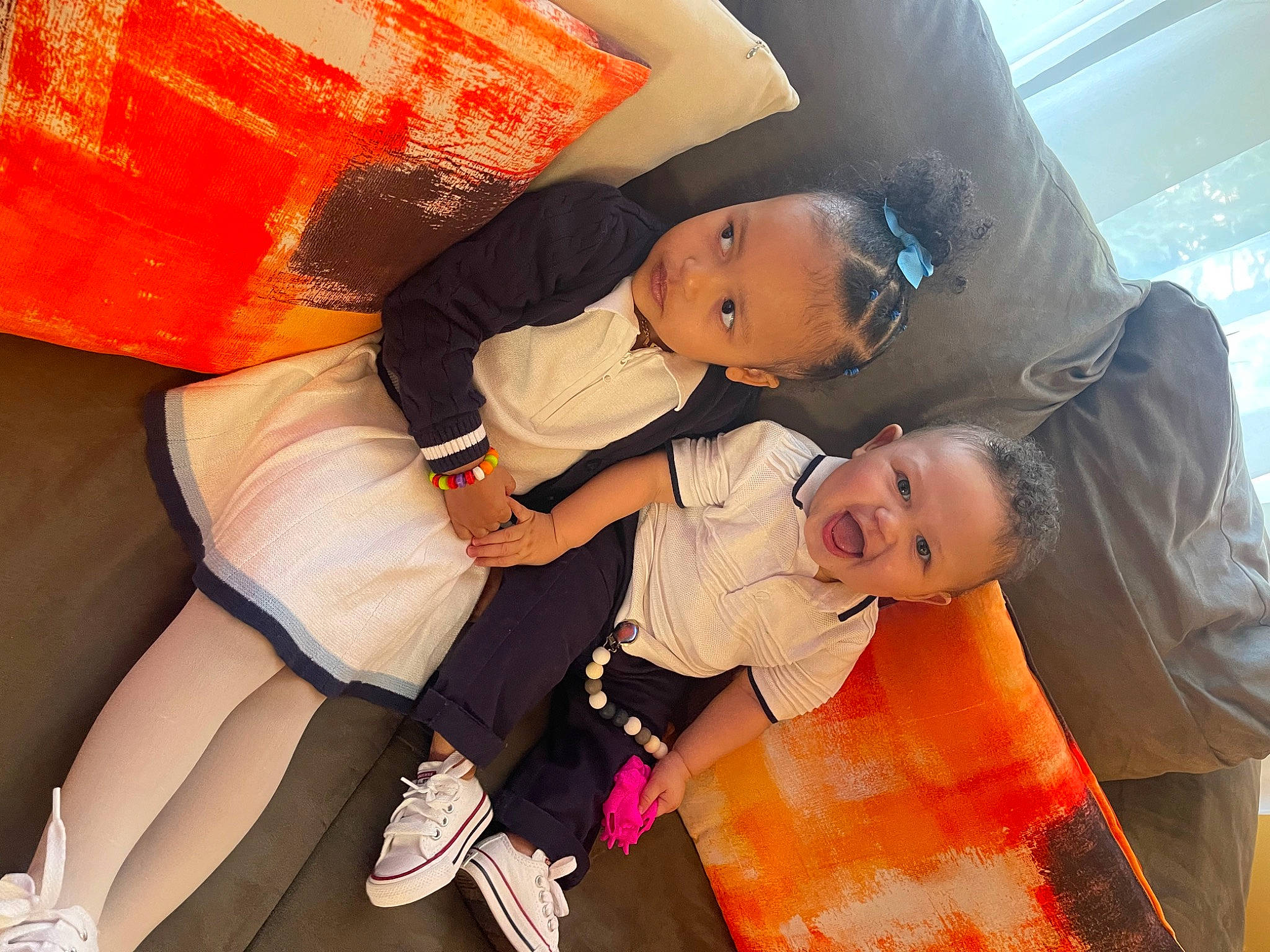 Amari is registered to the contest to win money with this photo: baby, baby_products, bag, child, comfort, event, flooring, fun, happy, hat, human_leg, lap, leisure, luggage_and_bags, orange, person, room, sitting, thigh, toddler