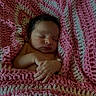 Izzariah is registered to the contest to win money with this photo: newborn, baby, sleeping, infant, portrait, blanket, bundled, peaceful, indoors, close_up, face, hands, closed_eyes, cozy, pink, textile, soft, resting, adorable, photography