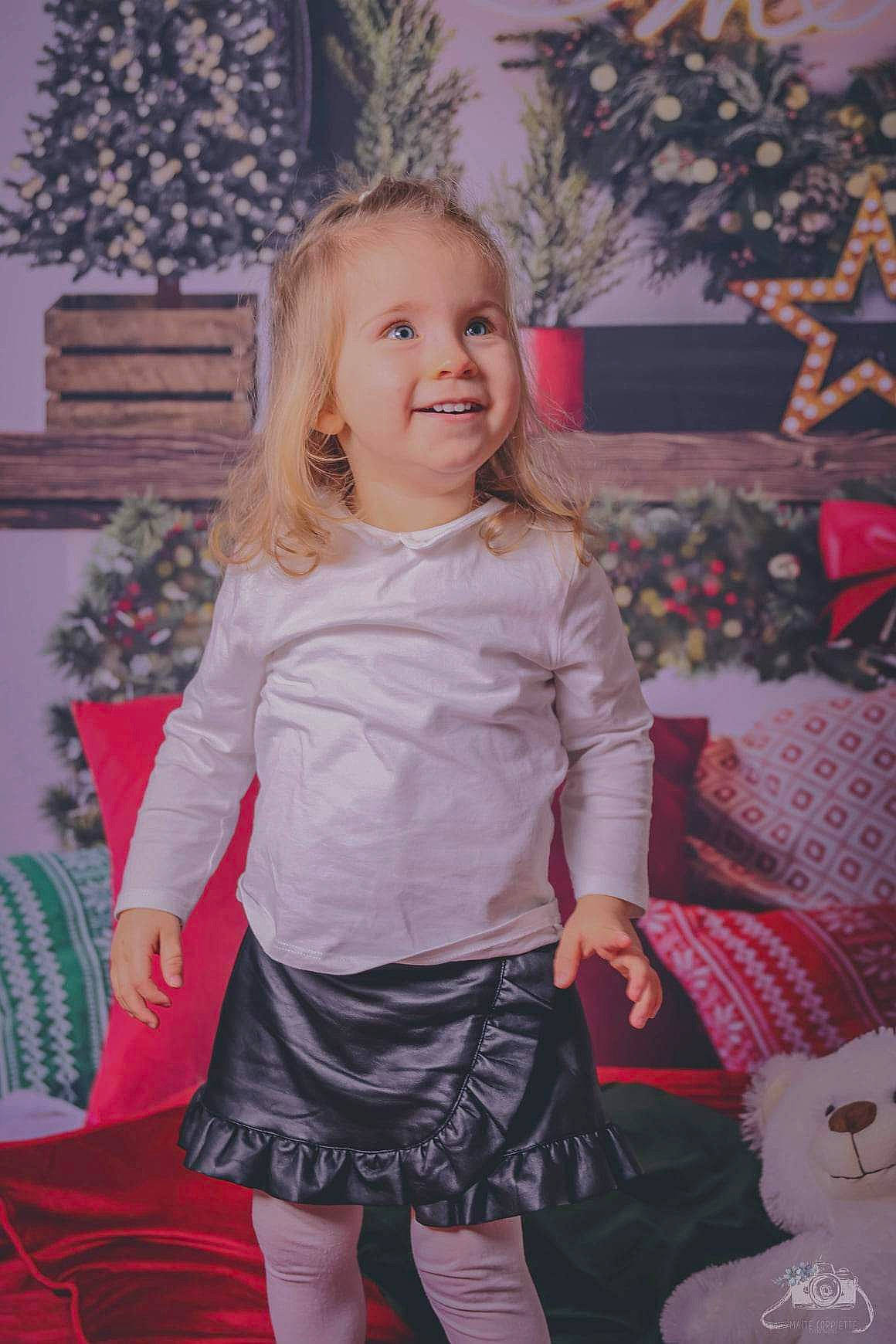 Mélina participe au concours pour gagner de l'argent avec cette photo : baby_toddler_clothing, blond, child, christmas_decoration, christmas_tree, event, hair, happy, holiday, iris, joy, long_hair, pattern, person, pink, plant, room, sleeve, smile, textile