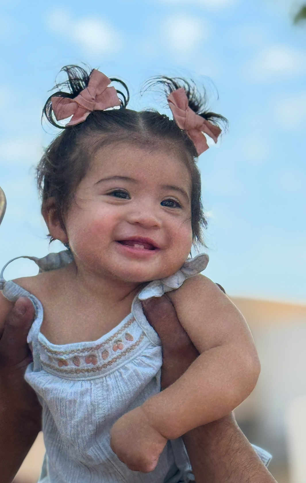 Milani joined the competition — help win amazing prizes! baby, child, smiling, girl, hair_bows, blue_sky, outdoor, cute, happy, portrait, person, hands, holding, clothing, white_dress, infant, face, skin, young, cheerful