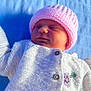 baby, newborn, pink_hat, knitted_sweater, floral_embroidery, blue_blanket, sleeping, peaceful, closeup, soft_light, child, infant, portrait, cozy, cute, warm_clothing, outdoor, texture, buttoned_sweater, resting