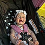 baby, child, stroller, smiling, headband, pink, polka_dot, harness, outdoor, sunlight, happy, infant, clothing, seatbelt, cute, person, portrait, cheerful, summer, babywearing