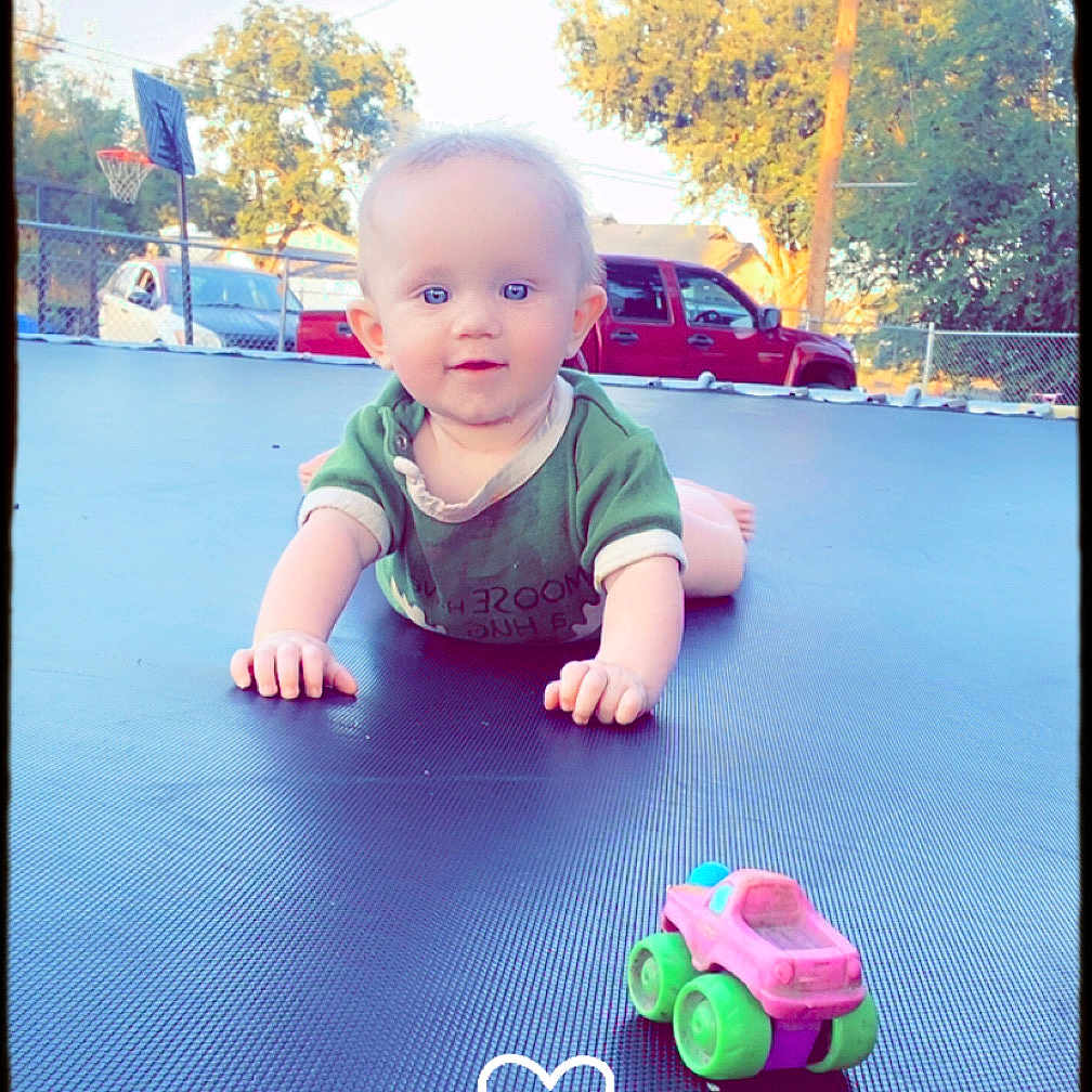 Lunna Rose joined the competition — help win amazing prizes! baby, backyard, basketball_hoop, car, child, crawling, curious, cute, daylight, fence, green_shirt, heart_doodle, outdoor, playtime, portrait, smiling, sunny, toy_car, trampoline, trees