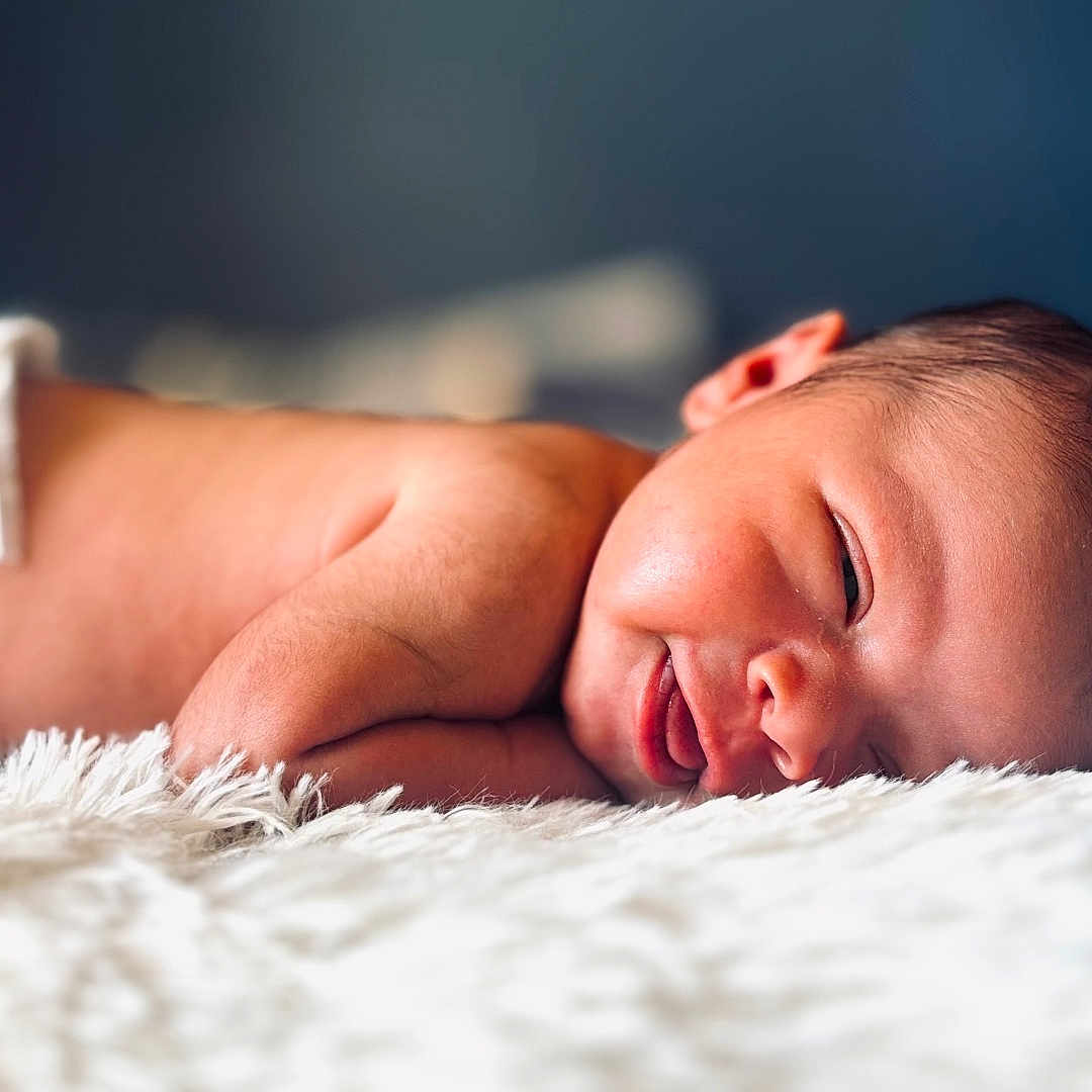 Kyzere is registered to the contest to win money with this photo: baby, bed, blanket, cheek, closeup, cute, diaper, face, fur, head, indoor, infant, lying_down, newborn, portrait, skin, sleeping, smile, smiling, soft_light