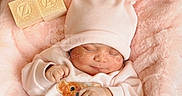 Zainab joined the competition — help win amazing prizes! baby, sleeping, pink, hat, blanket, wooden_blocks, teddy_bear_print, clothing, infant, soft_texture, cute, cozy, child, portrait, newborn, resting, indoor, hands, face, babywear