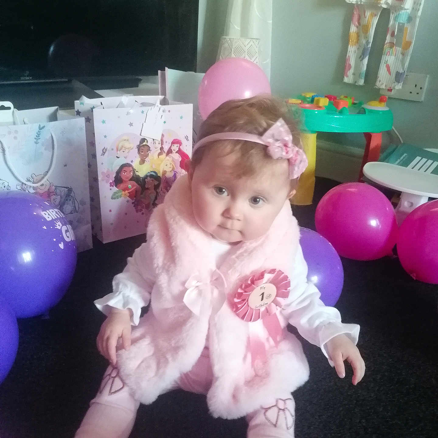Esme is registered to the contest to win money with this photo: baby, balloons, birthday, carpet, celebration, child, curtain, first_birthday, floor, gift_bags, girl, headband, indoor, party, pink, ribbon, shoes, toy_table, vest, wall_socket