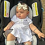 baby, infant, child, car_seat, white_clothing, headband, bow, bracelet, socks, outdoor, pavement, seatbelt, cute, young_child, portrait, sitting, accessories, baby_girl, expression, comfort