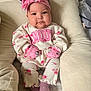 baby, baby_socks, beige, child, clothing, comfortable, cushion, cute, face, floral_clothing, headband, indoors, infant, mittens, person, pink, portrait, sitting, soft_lighting, young_child