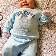 Viviana joined the competition — help win amazing prizes! baby, child, infant, smiling, lying_down, pajamas, blue_clothing, hello_kitty, mittens, bedspread, floral_pattern, cute, face, happy, indoor, person, soft_lighting, cozy, cartoon_character, eeyore