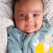 Maïtê participe au concours pour gagner de l'argent avec cette photo : baby, infant, smile, blue_onesie, bow, blanket, cozy, cute, portrait, child, face, happy, lying_down, soft_texture, warm_clothing, indoors, toddler, closeup, adorable, peaceful